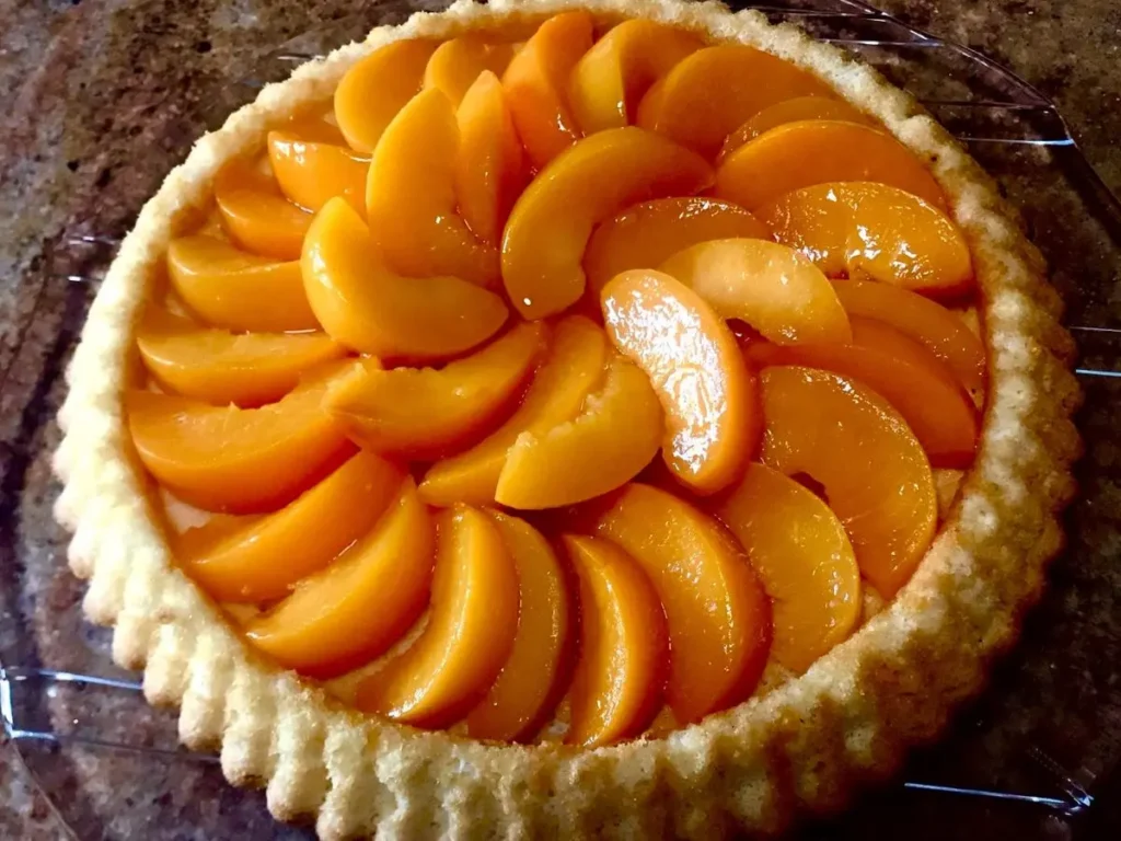 Homemade peach flan topped with glossy peach slices
