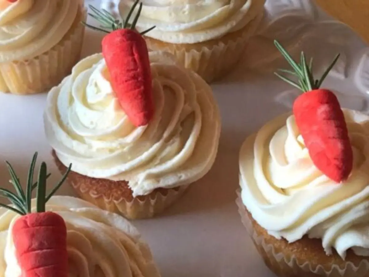 Vanilla cupcakes with buttercream frosting topped with handmade gum paste carrots.