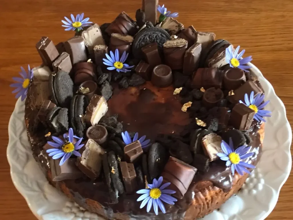 Classic German Chocolate cheesecake decorated with biscuits, chocolates, and flowers – creative baking and party ideas.