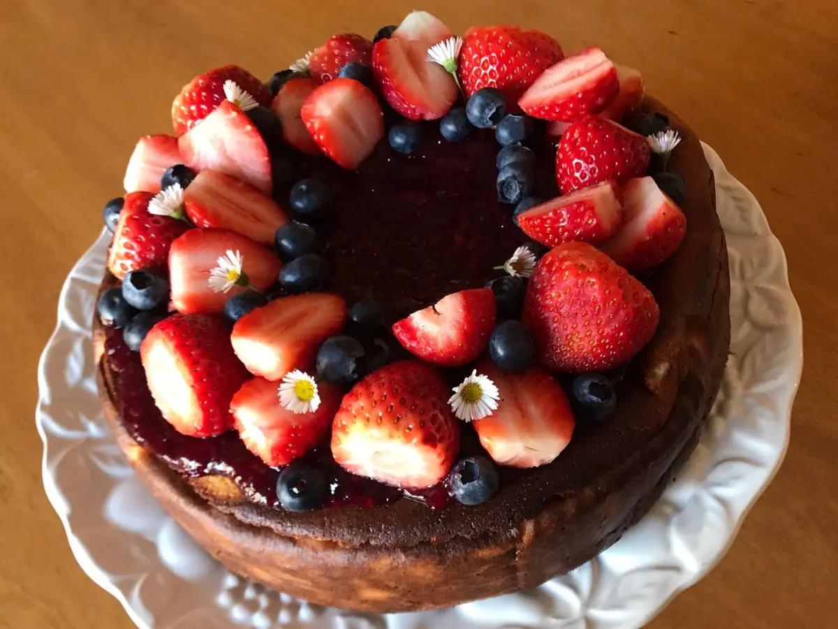 German Cheesecake Recipe topped with berry sauce, fresh strawberries, and blueberries.