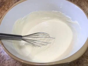 Mixing egg yolks, sugar, cream cheese, and sour cream