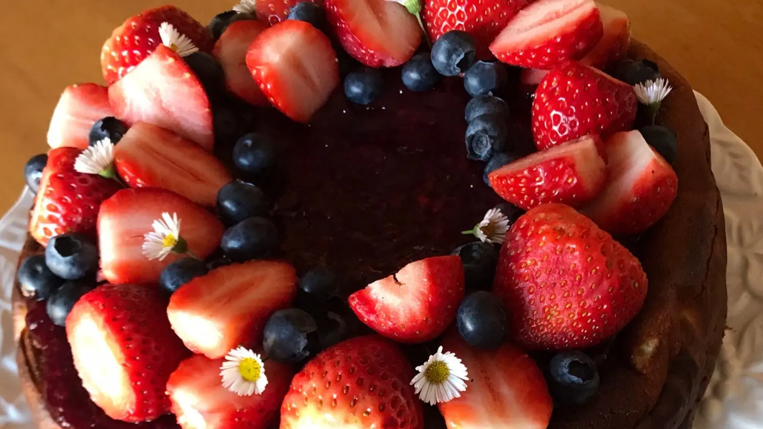 German Cheesecake Recipe topped with berry sauce, fresh strawberries, and blueberries.