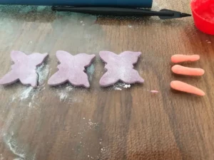 Rolling a small amount of gum paste into a sausage shape to form the butterfly thorax.