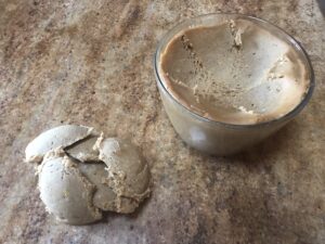 Brown Syrupkuchen dough in a mixing bowl, with a firm portion set aside in a cracked ball on a kitchen counter.