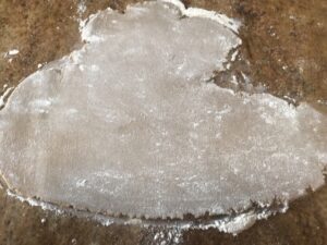 Firm Syrupkuchen dough rolled out on a floured surface, ready to be cut with cookie cutters.