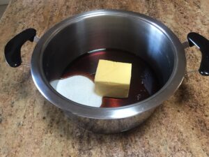 A pot with syrup, butter, and sugar on a kitchen counter, ready to be melted for Syrupkuchen cookie dough.