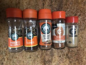 Assorted ground spices used in Syrupkuchen, including cinnamon, ginger, cloves, and allspice.