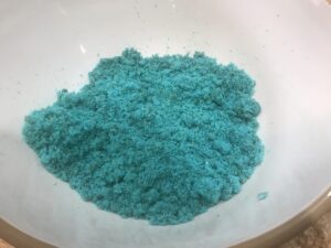 Bright blue cake crumbs in a white mixing bowl, ready to be used in a fun cake pop recipe for kids.