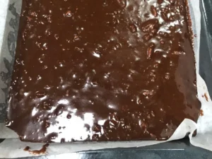 Chocolate pecan brownie batter spread evenly in a lined baking tray