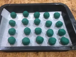 Uncoated blue cake balls arranged on a baking tray.