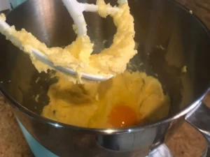 Adding eggs one at a time to the creamed butter and sugar mixture
