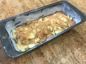 Unbaked apple cinnamon loaf cake batter in a loaf pan with cinnamon swirl