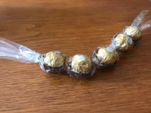 Ferrero Rocher chocolates connected in a curved line using cellophane and twine