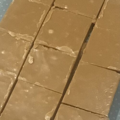 Homemade fudge cut into squares, displayed on a polka dot surface, perfect as a sweet party favour.