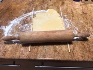 Rolling out German tea biscuit dough between wooden guides