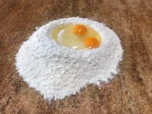 Eggs placed in a well of flour for German tea biscuit dough