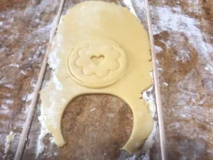 Rolling out biscuit dough and cutting German tea biscuits with a decorative cookie cutter
