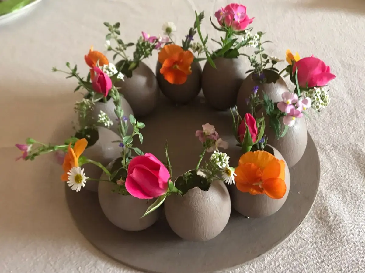 Rustic DIY Easter egg centrepiece made from real eggshells painted in soft taupe, arranged in a circular wreath and filled with colourful fresh garden flowers.