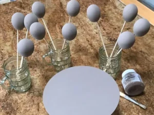 Applying Coco chalk paint to an eggshell and wooden circle with a paint brush