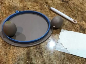 Embroidery hoop and blown egg used to prepare a DIY Easter centrepiece decoration.