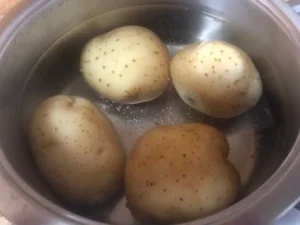 Whole potatoes boiling in a pot for warm potato salad