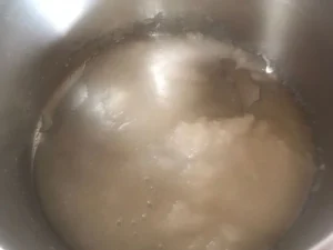 Sugar and water mixture beginning to melt in a stainless steel saucepan.