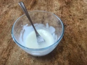 Egg white and icing sugar mixture in a glass bowl with a fork, before adding tylose powder.
