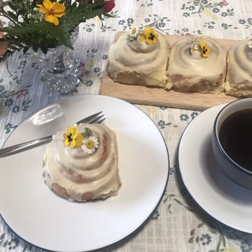 Iced cinnamon roll with edible flowers and coffee