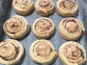 Unbaked cinnamon rolls in a baking tray before their second rise, tightly coiled with visible butter and cinnamon-sugar filling.