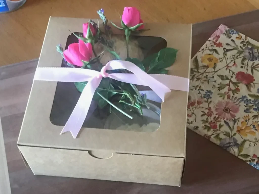 Decorating a gift box of homemade scones with pink ribbon and fresh roses.