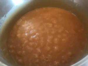 Thick, golden fudge bubbling vigorously in a saucepan.