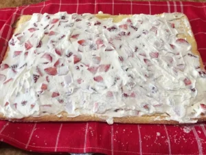 Strawberry and cream filling spread evenly over the Swiss roll sponge