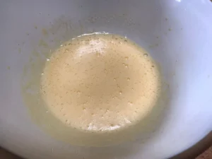Pale and foamy egg yolk mixture in a mixing bowl, ready for the next step of the strawberries and cream swiss roll.