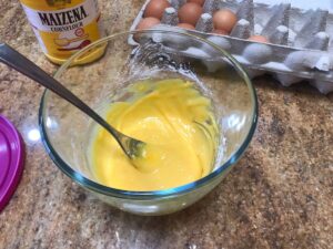 Cornflour and egg yolk mixture in a glass bowl with a spoon, ready for making a delicious Pastry Cream Recipe.