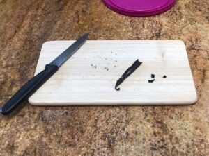 Pastry Cream Recipe - Split vanilla bean on a small wooden cutting board next to a knife.