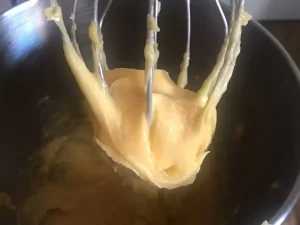 Choux pastry dough clinging to a stand mixer whisk attachment.
