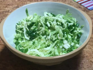 Shredded cabbage mixed with sliced sugar snap peas and chopped spring onions
