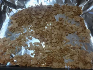 Slivered almonds and crushed two-minute noodles toasted on a baking tray