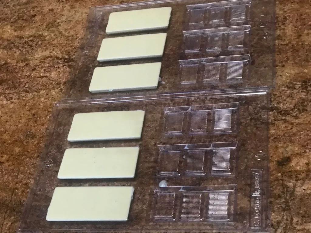 Mini chocolate slabs setting in clear plastic moulds for handmade thank you gifts.