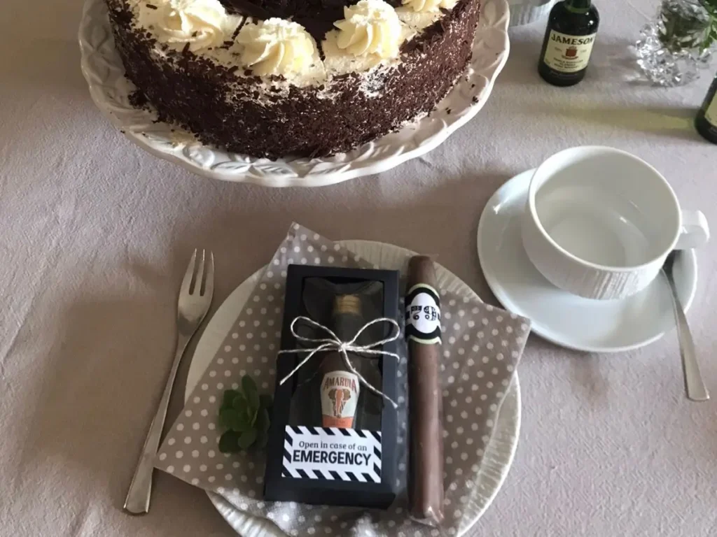 Black Forest cake with cream swirls and an “In Case of Emergency” mini alcohol party favour on a polka dot napkin.