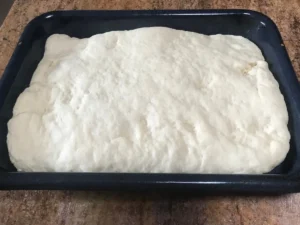 Butterkuchen dough risen in a baking tray before baking.