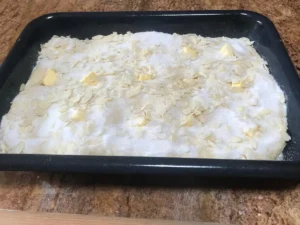 Butterkuchen topped with sugar almonds and butter before baking.