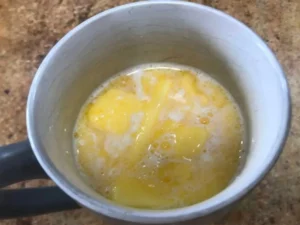Melted butter and milk mixture in a mug for yeast dough.