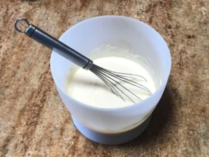 Whisking yoghurt eggs vanilla essence and sugar for oats and apple breakfast cake