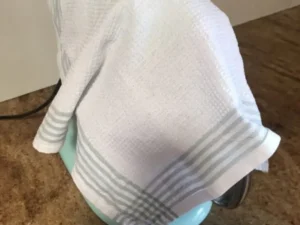 Bowl of cream cheese frosting covered with a cloth while mixing