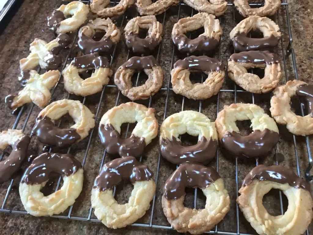 Spritzgebäck cookies dipped in chocolate drying on cooling rack