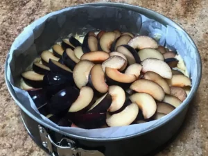 Plums arranged on batter for German plum cake