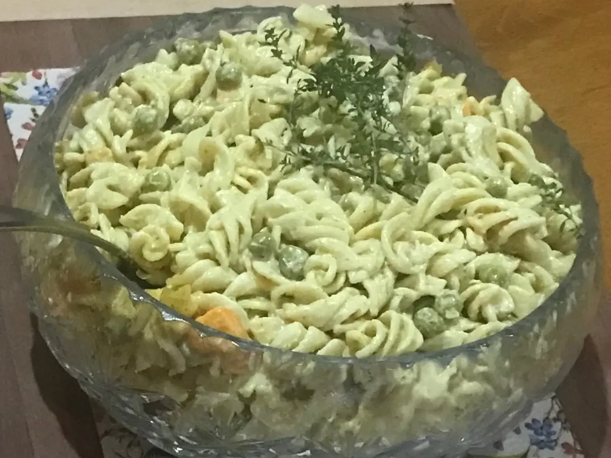 Creamy curried pasta salad with peaches and peas served in a glass bowl