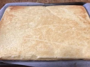 Swiss roll sponge with baking paper removed, and now needs to be rolled.