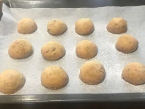 Warm Pecan Balls being sprinkled with icing sugar after baking.